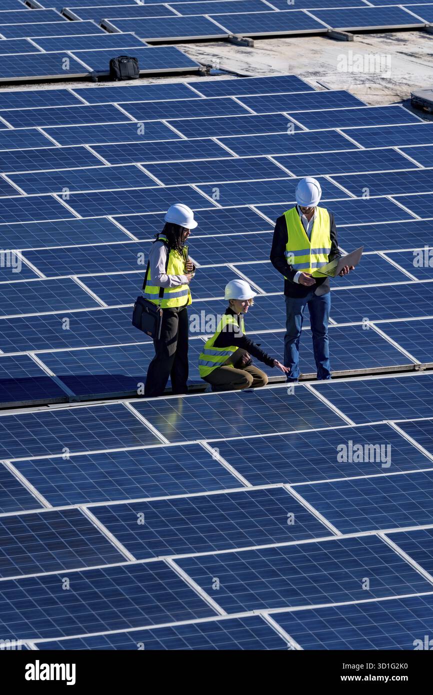 Engineers and technicians inspecting solar panels on a large solar farm ...