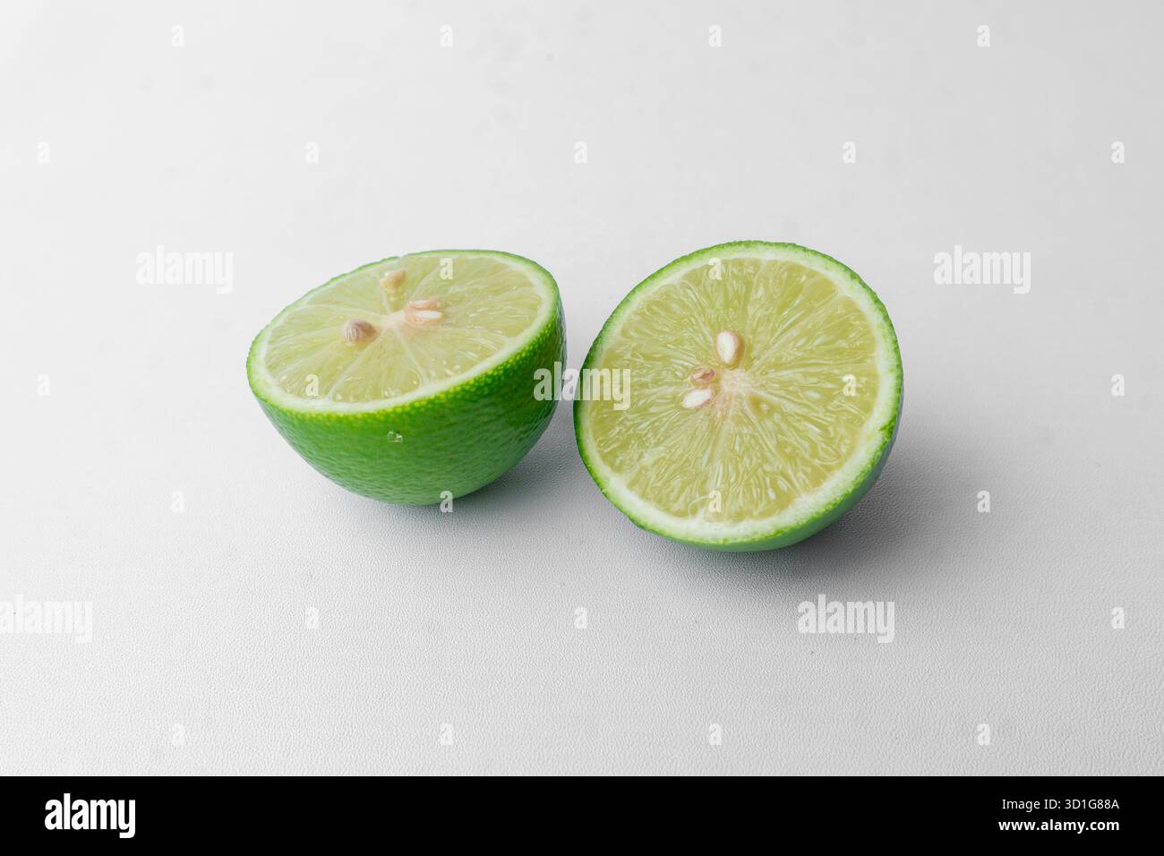 A fresh green lime cut in two halves. Isolated on a clean white studio background. Healthy citrus fruit. Minimalist with copy space. Stock Photo