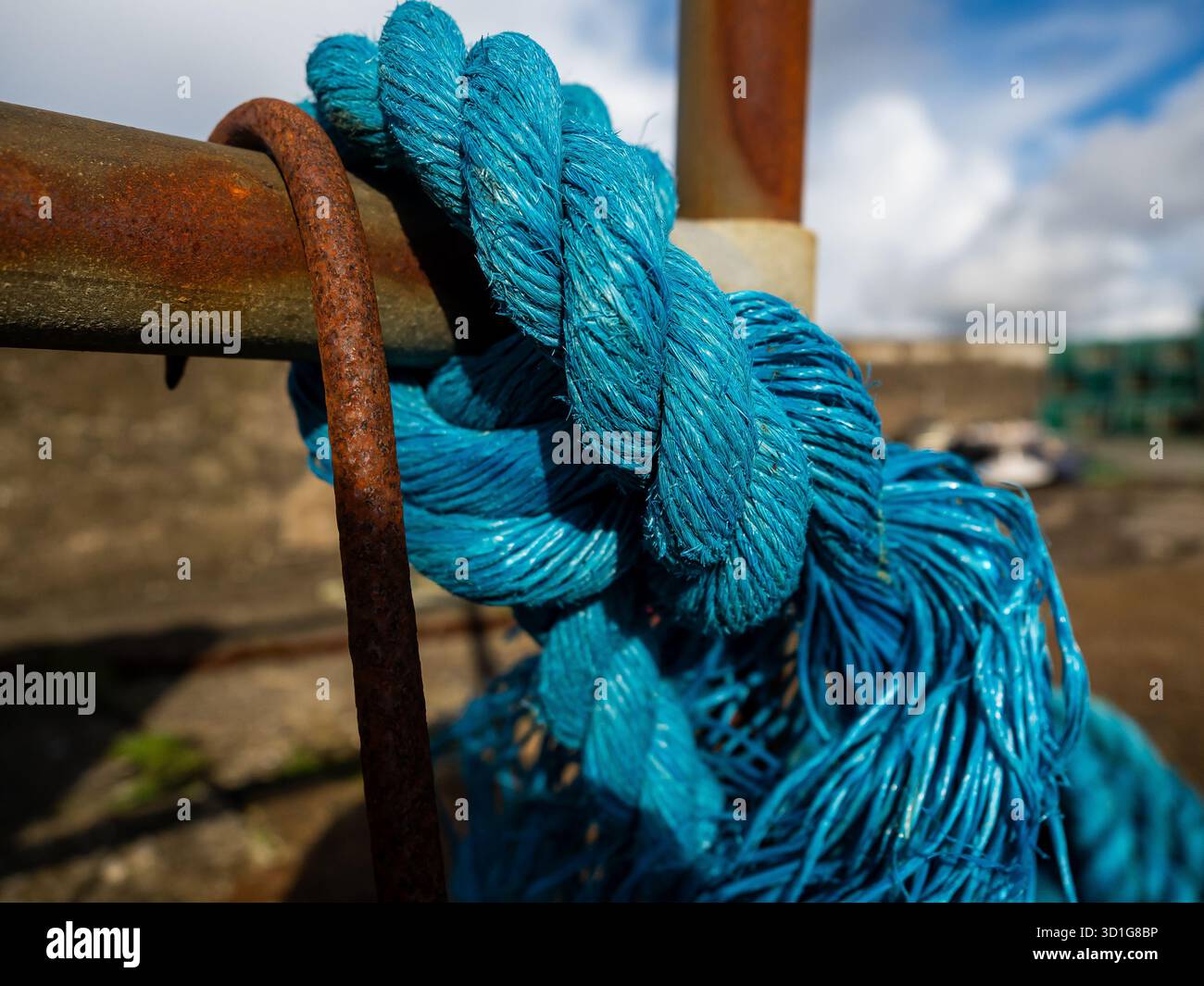 Close up of blue rope tied around a rusty metal bar Stock Photo