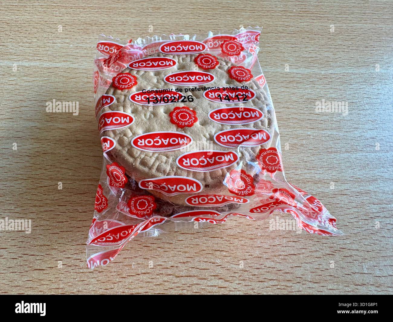 Packaged biscuit in transparent plastic wrapper with red branding on a wooden surface. - Smartphone Captured Stock Image