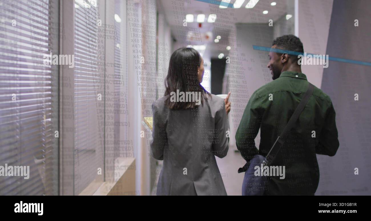 Walking two professionals side-by-side down office hallway, with notebook, messenger bag, blinds Stock Photo