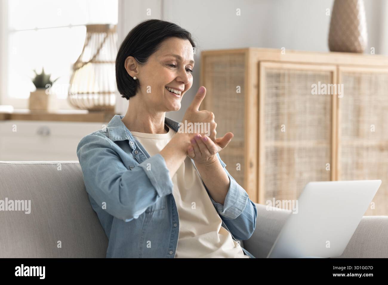 Senior woman communicating by videocall via notebook using sign language Stock Photo