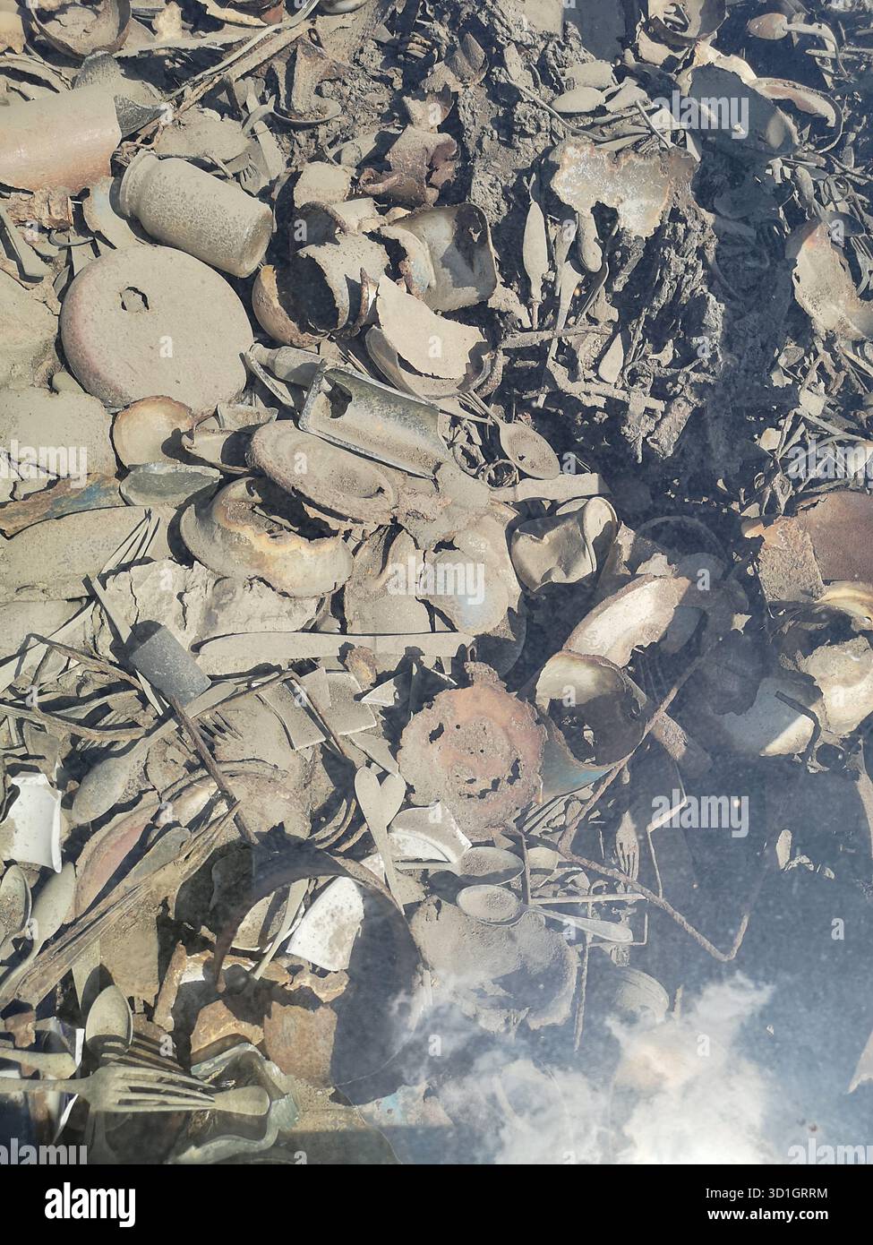 Scissors, trinkets, treasured items and utensils literally embedded in the ground at Auschwitz-Birkenau’s Kanada barracks—now preserved under glass. - Smartphone Captured Stock Image