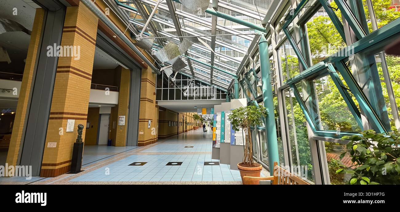 Belin, Germany - May 30, 2025: Modern shopping mall features a glass roof and lush greenery throughout the space. Hospital - Smartphone Captured Stock Image