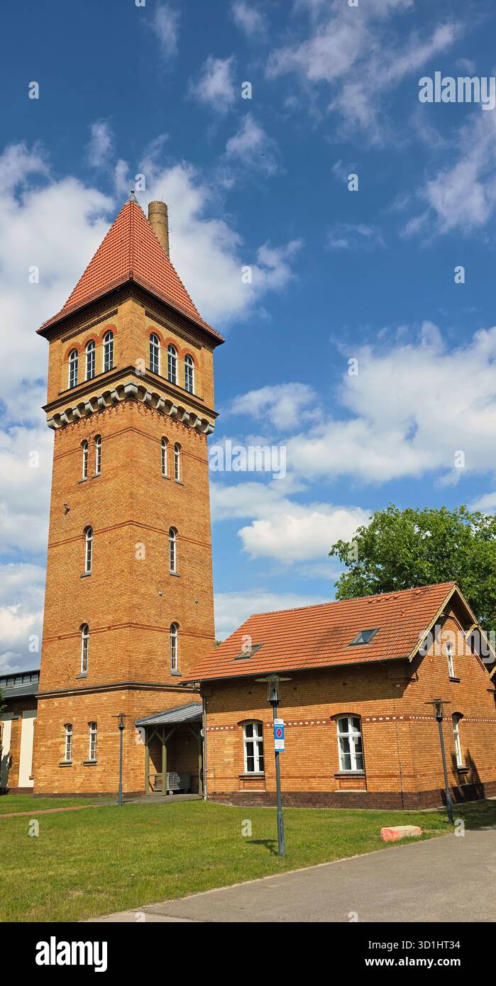 Belin, Germany - May 30, 2025: Historic brick tower building features a red roof and is set against a blue sky backdrop. Hospital - Smartphone Captured Stock Image