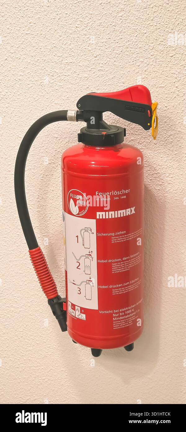 Belin, Germany - May 30, 2025: Red fire extinguisher is mounted on wall with clear safety instructions visible. Hospital - Smartphone Captured Stock Image