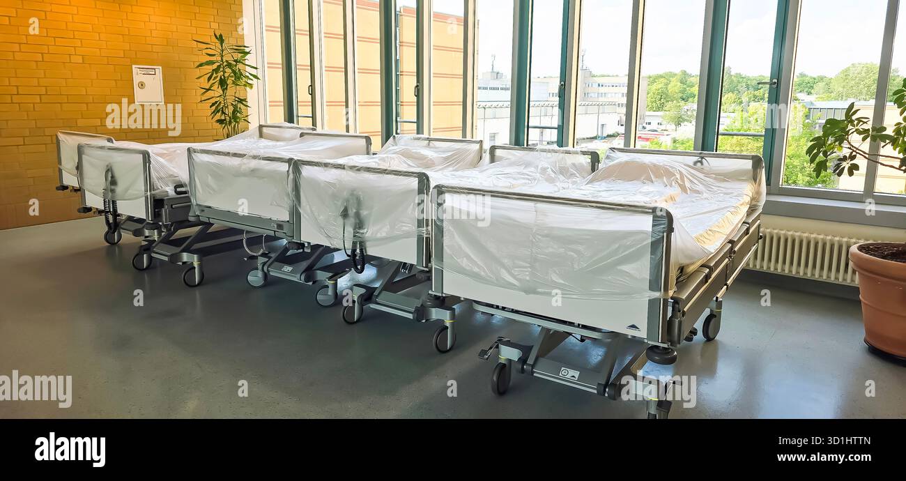 Belin, Germany - May 30, 2025: Hospital patient beds are arranged in a bright room with large windows and greenery. Hospital - Smartphone Captured Stock Image