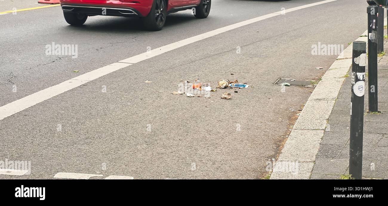 Belin, Germany - May 19, 2025: Litter scattered on urban street with passing cars and pavement visible nearby. - Smartphone Captured Stock Image