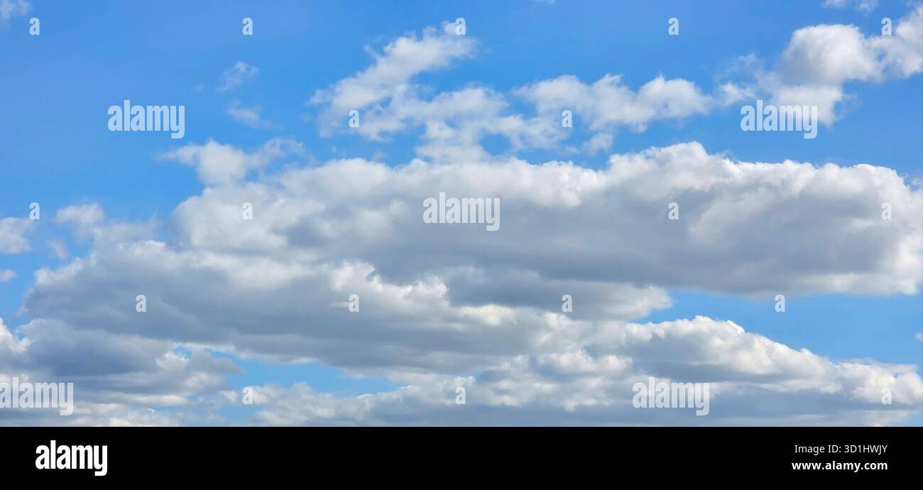 Soft white clouds are drifting across a bright blue sky, illuminated by gentle sunlight, creating a serene and peaceful atmosphere. - Smartphone Captured Stock Image