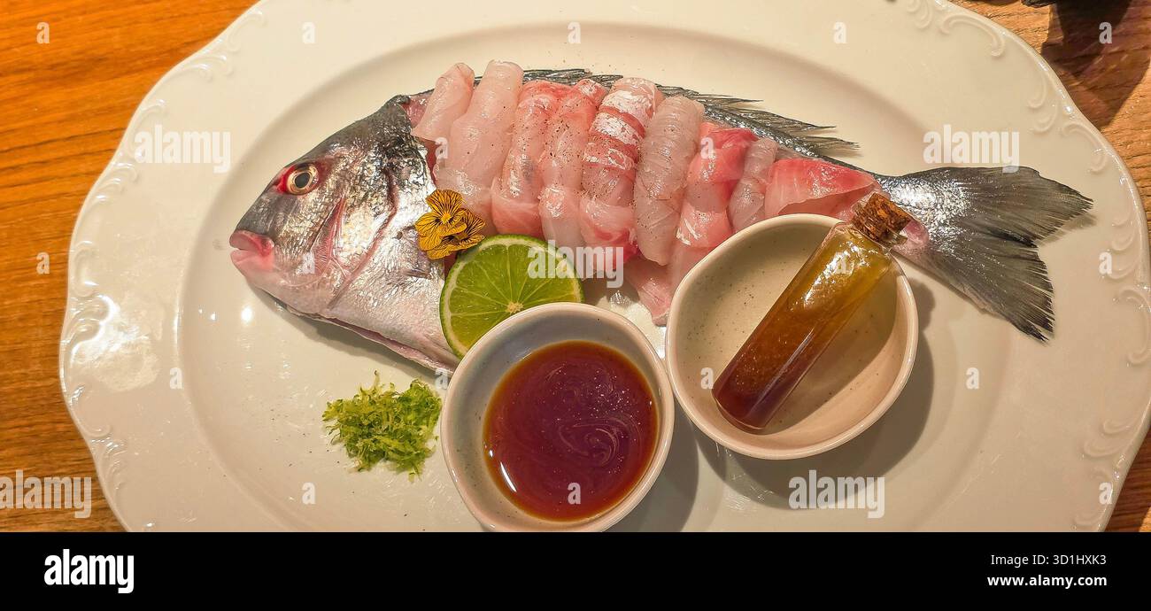 Freshly prepared fish dish, elegantly arranged with garnishes, lime, and dipping sauces, showcasing culinary artistry and vibrant presentation. - Smartphone Captured Stock Image
