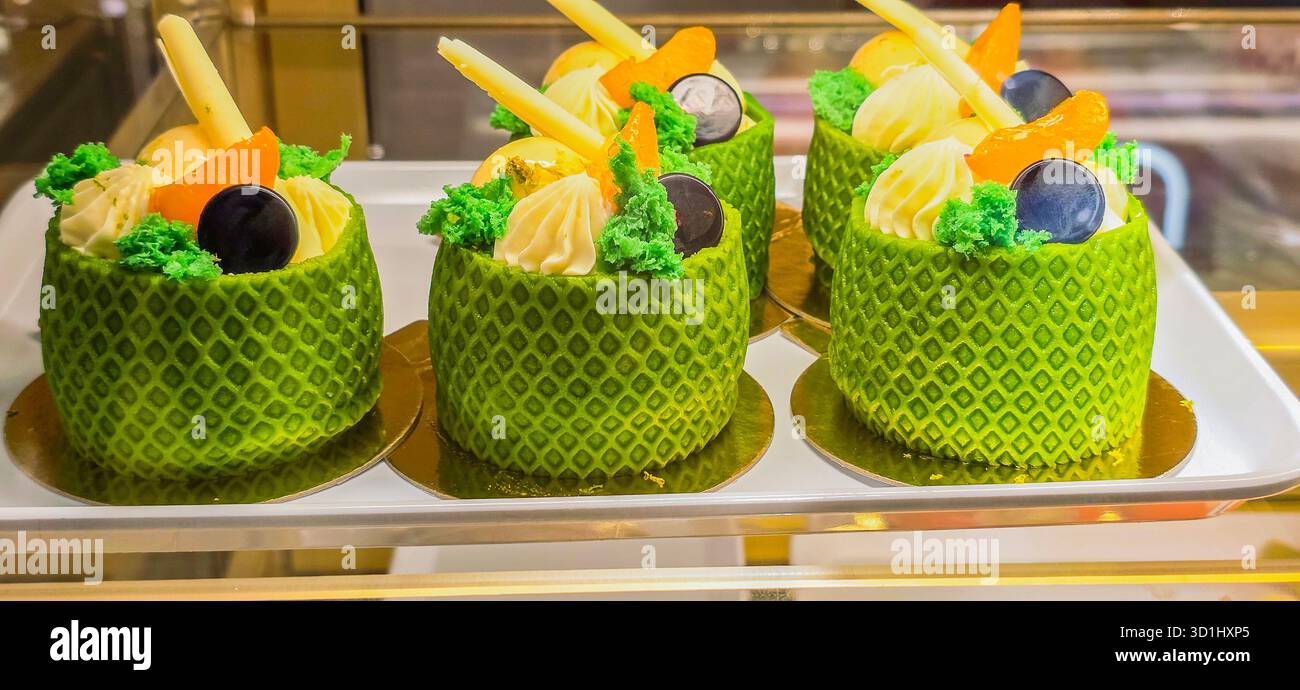 Colorful dessert cakes are beautifully arranged on a tray, featuring vibrant toppings and intricate decorations, showcasing culinary artistry. - Smartphone Captured Stock Image