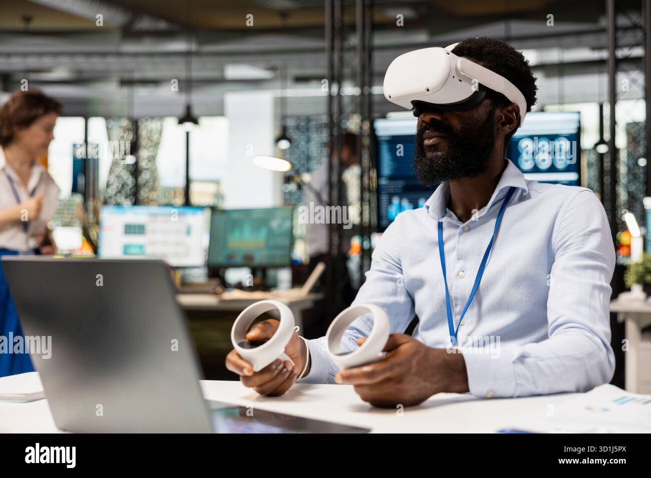 African American executive wears VR headset and holds controllers during interactive meeting on business analytics. Black man financial planning using virtual technology in modern office. Stock Photo