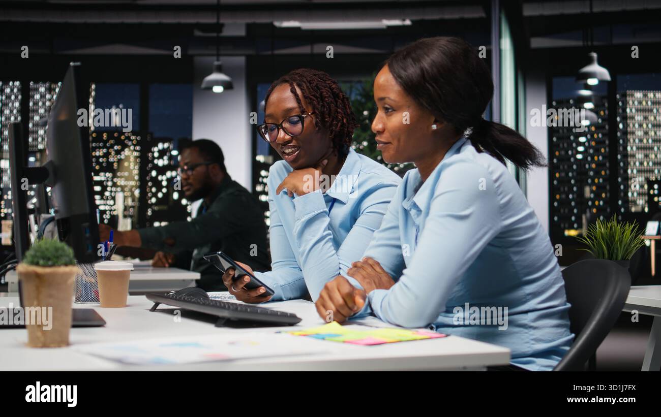 Black women working together with data insights on desktop in workspace, developing business solutions with strategy planning and performance metrics analysis for new goals achievement. Stock Photo