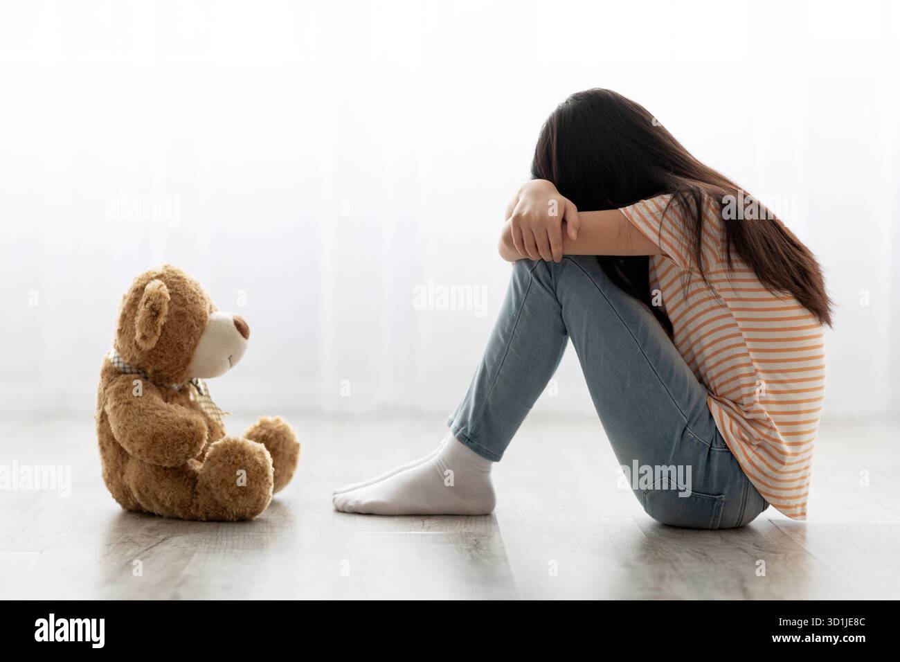 Girl Sitting on the Floor With Her Knees Pulled to Her Chest Next to a ...