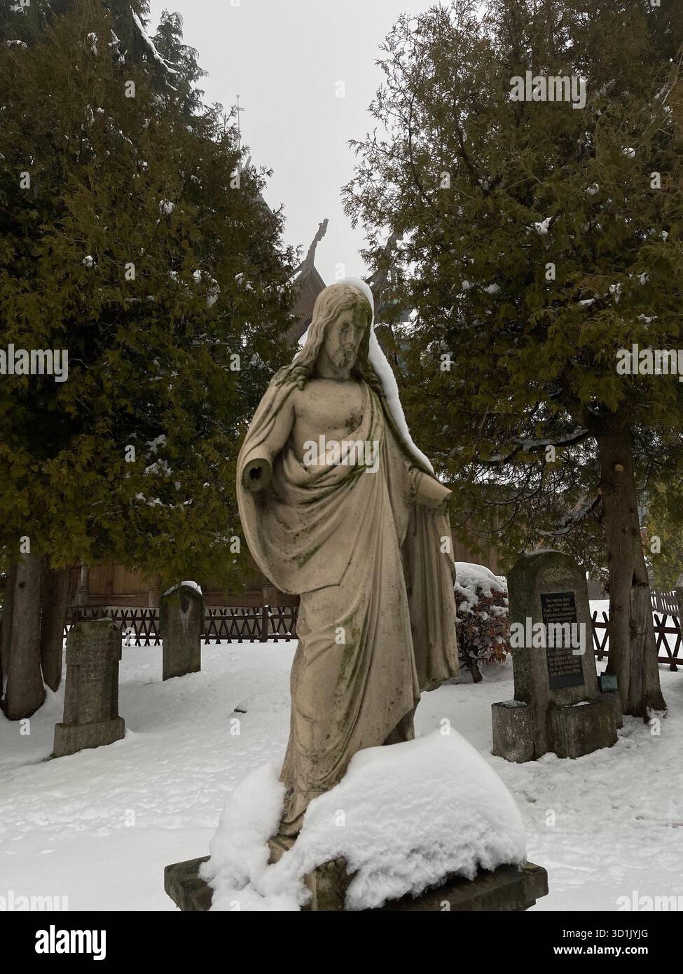 Snow-covered statue of Jesus Christ located in the historic cemetery area near Wang Church in Karpacz, Poland. A winter landscape - Smartphone Captured Stock Image