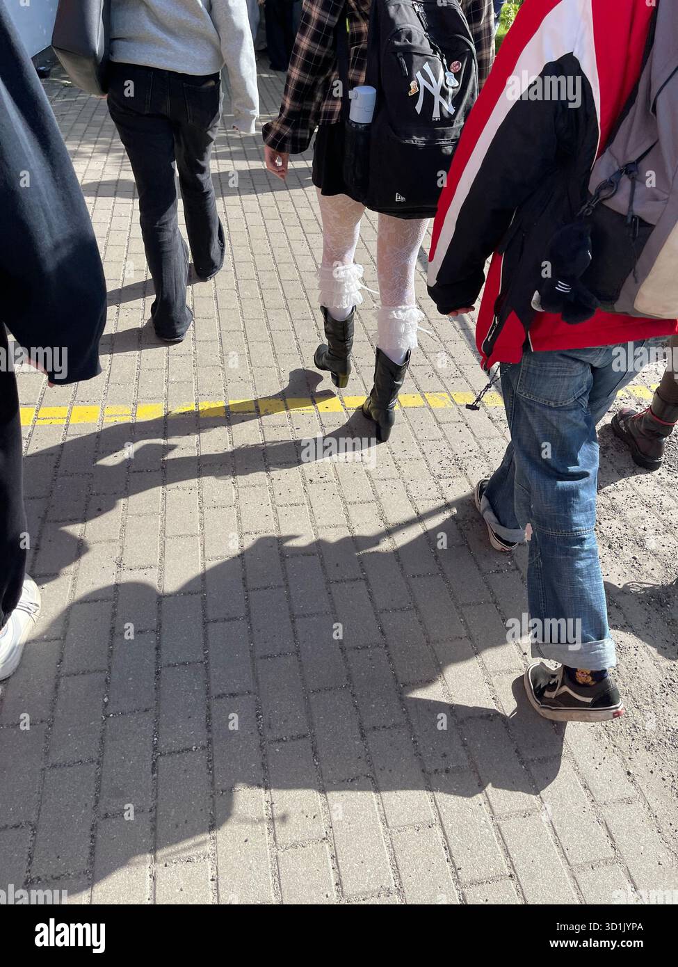 Pedestrians’ legs and long shadows on street pavement in bright sunlight. - Smartphone Captured Stock Image