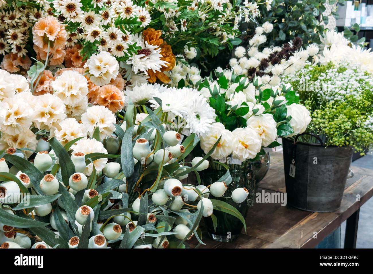 Assorted white and pastel faux florals including roses, daisies, and lotus pods in display. Budget-friendly decor for hospitality and retail, faux Stock Photo