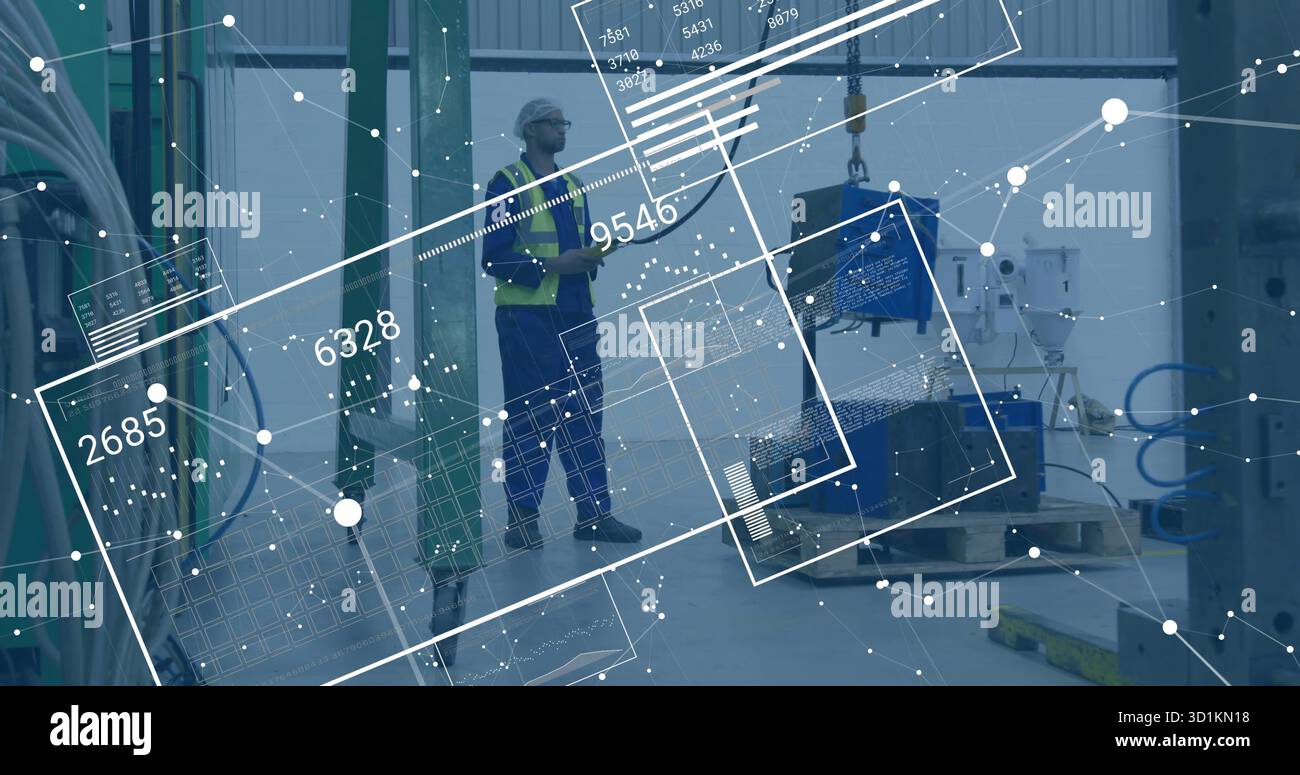 Factory tech in helmet and vest examining component hanging from crane hook, with data overlays Stock Photo