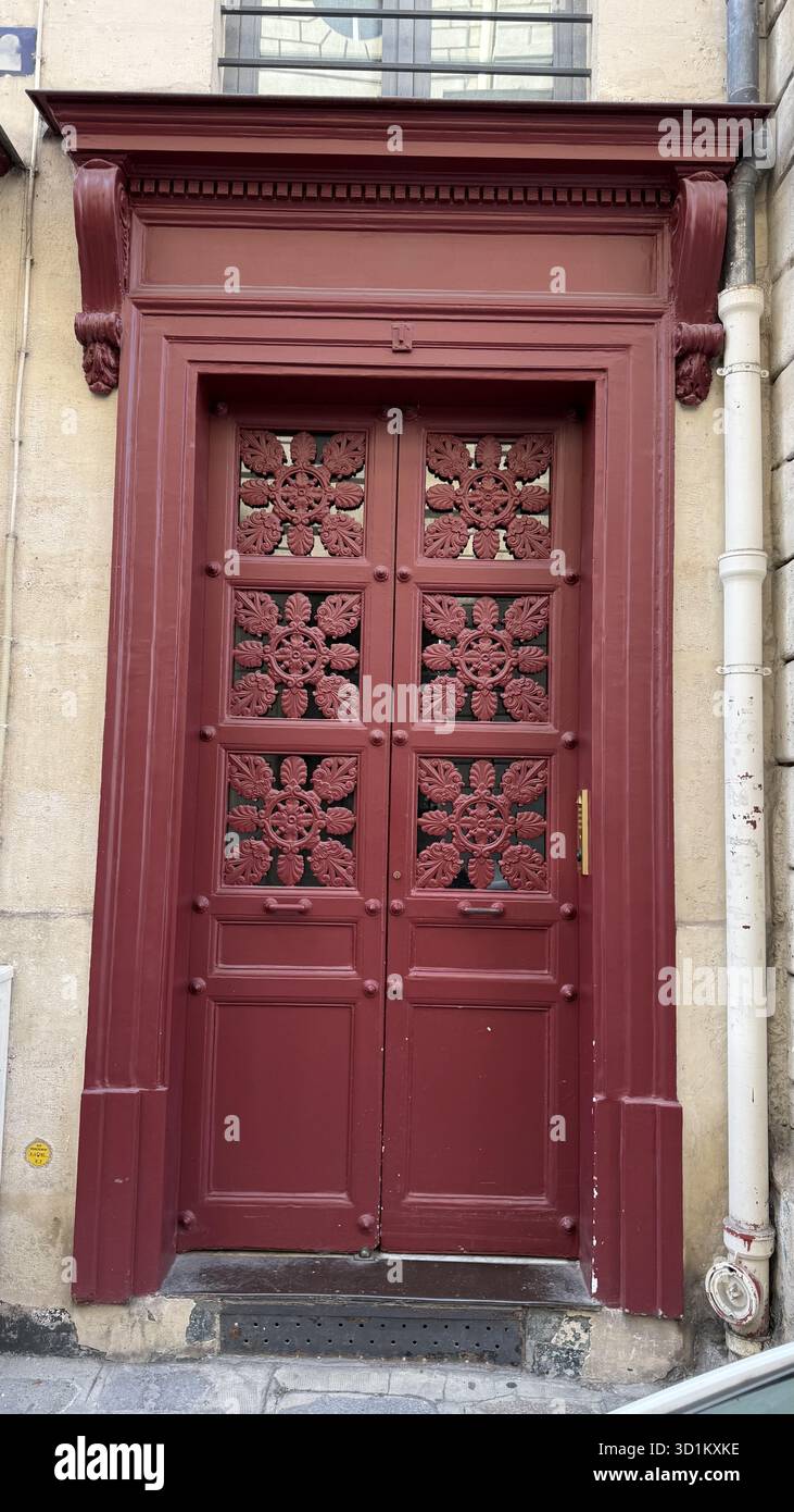 Red wooden door with elegant carved details on a historic stone ...