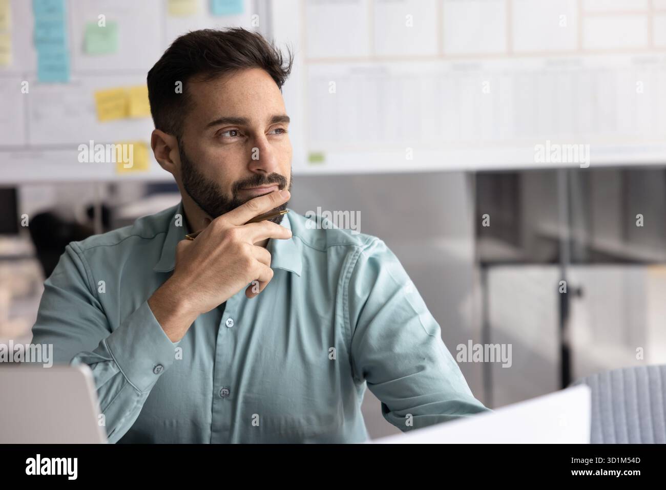 Male business planner looking aside from notebook holding papers pen Stock Photo