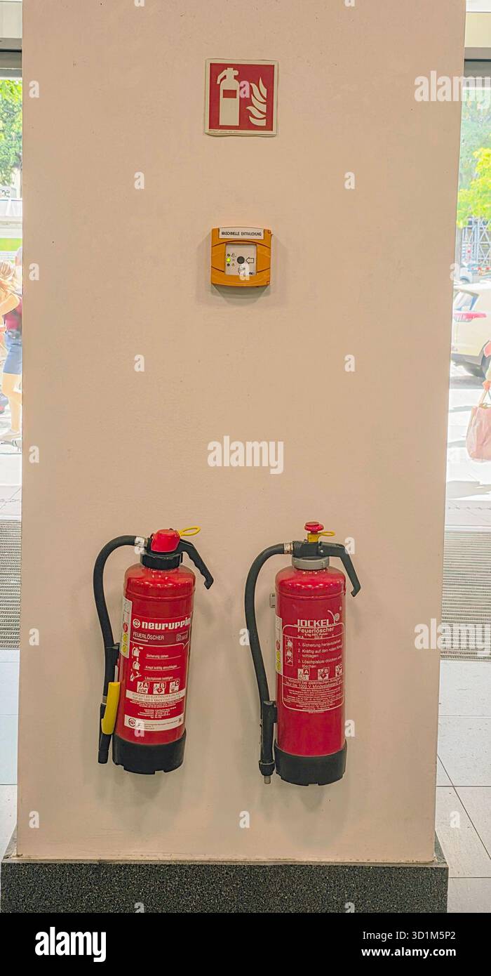 Fire extinguishers are mounted on a wall, accompanied by a fire alarm system, ensuring safety and preparedness in the environment. - Smartphone Captured Stock Image