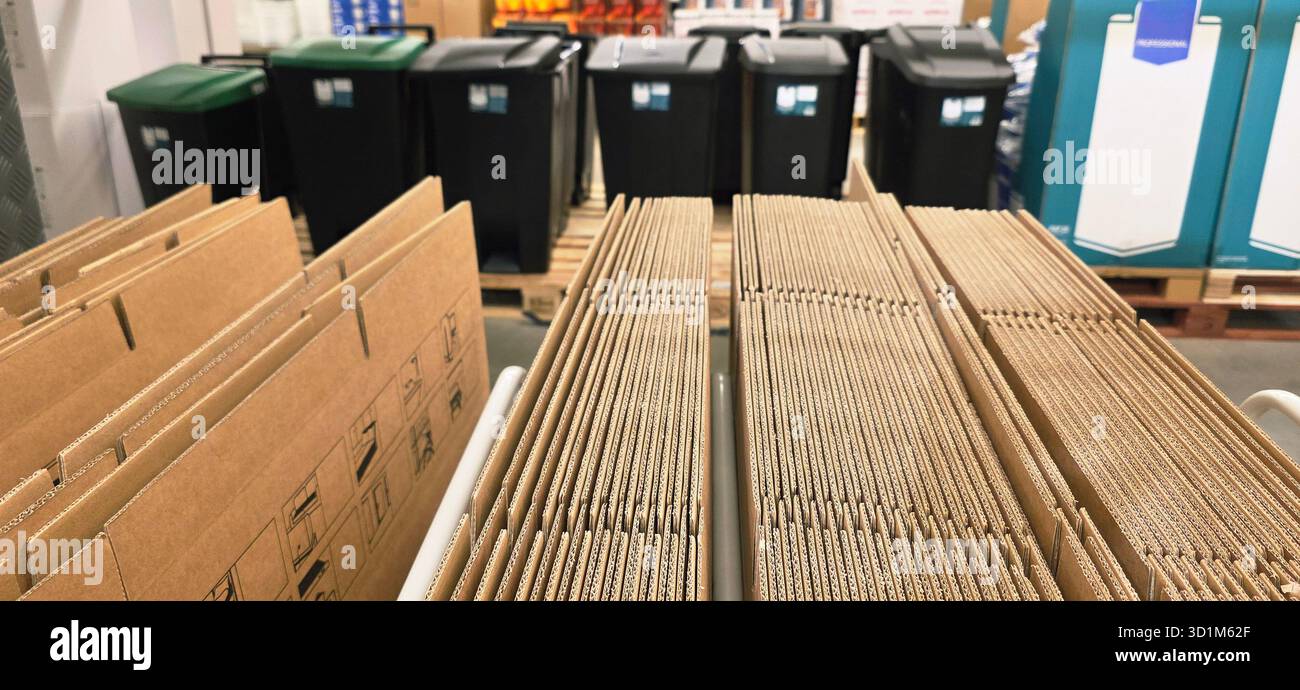 Cardboard boxes are organized in a warehouse, with trash bins positioned behind, showcasing an orderly storage environment. - Smartphone Captured Stock Image