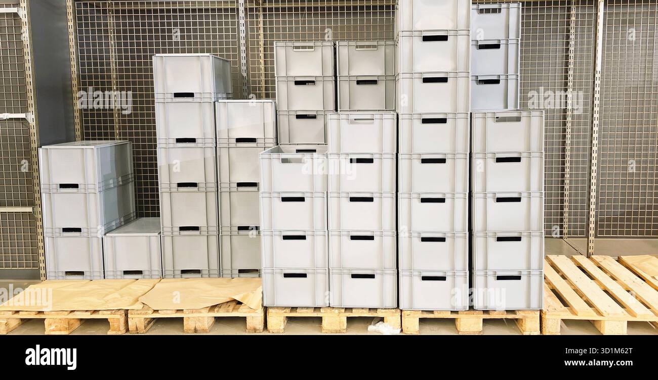 Stacked storage boxes are arranged on wooden pallets in a well-organized warehouse, showcasing efficient use of space and storage solutions. - Smartphone Captured Stock Image