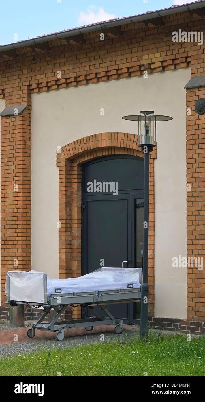 Belin, Germany - May 30, 2025: Hospital stretcher is positioned outside a building with modern architecture and green grass. Hospital - Smartphone Captured Stock Image