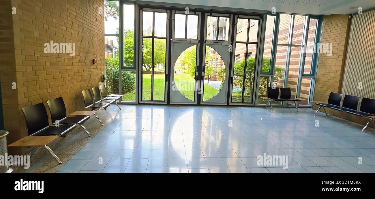 Belin, Germany - May 30, 2025: Spacious lobby features large circular windows and a view of the green garden outside. Hospital - Smartphone Captured Stock Image