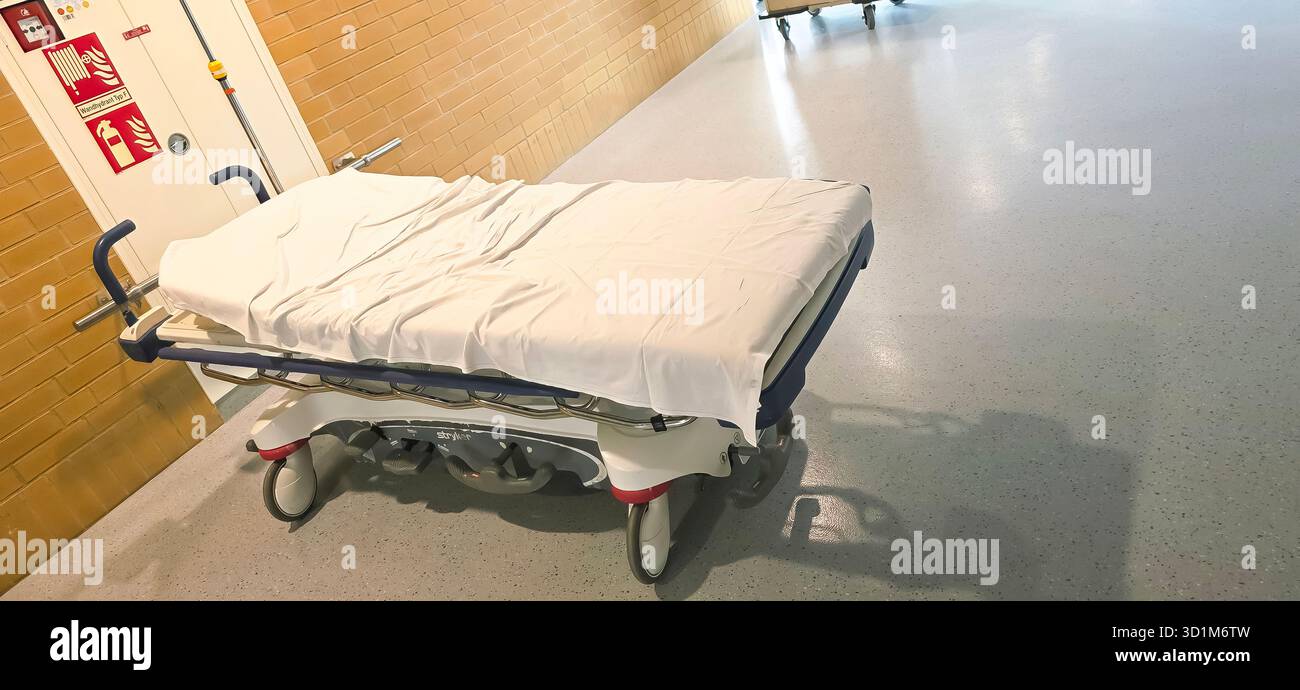 Belin, Germany - May 30, 2025: Hospital gurney covered with white sheet in empty corridor with copy space. Hospital - Smartphone Captured Stock Image