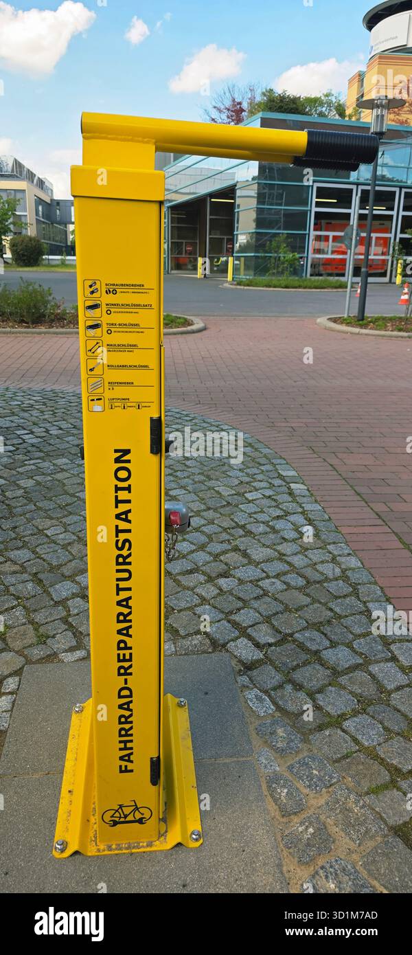 Belin, Germany - May 30, 2025: Yellow bike repair station stands in urban area with modern buildings in background. Hospital - Smartphone Captured Stock Image