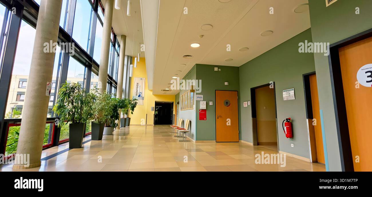 Berlin, Germany - June 16, 2025: Modern hallway features large windows and green plants in a contemporary building. - Smartphone Captured Stock Image