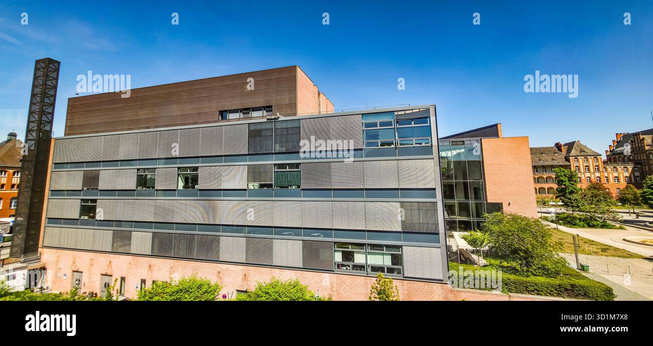 Berlin, Germany - May 13, 2025: Modern architectural structure features green landscaping and clear blue sky in the background. - Smartphone Captured Stock Image