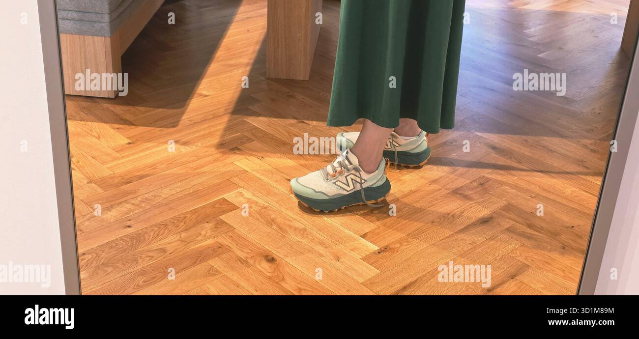 Berlin, Germany - June 13, 2025: Woman in New Balance sneakers stands on wooden floor, reflected in mirror. - Smartphone Captured Stock Image