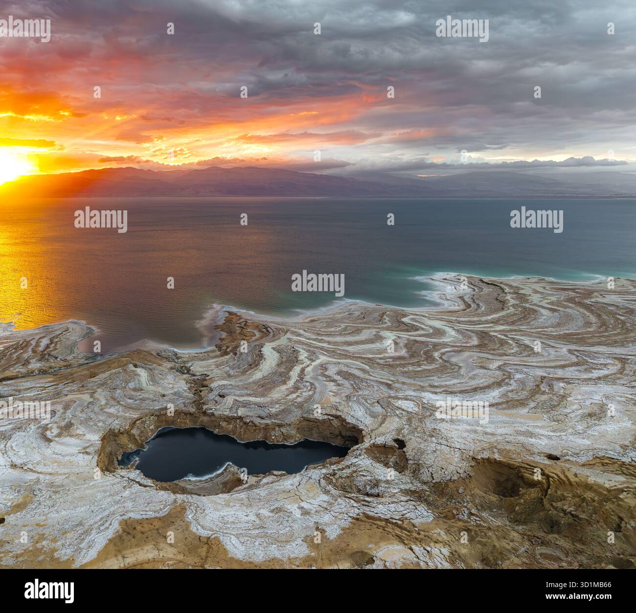 Aerial view of the Dead Sea's mesmerizing shoreline where the vibrant sunset paints the sky as it meets the unique salt formations, Ein Gedi, Israel. Stock Photo
