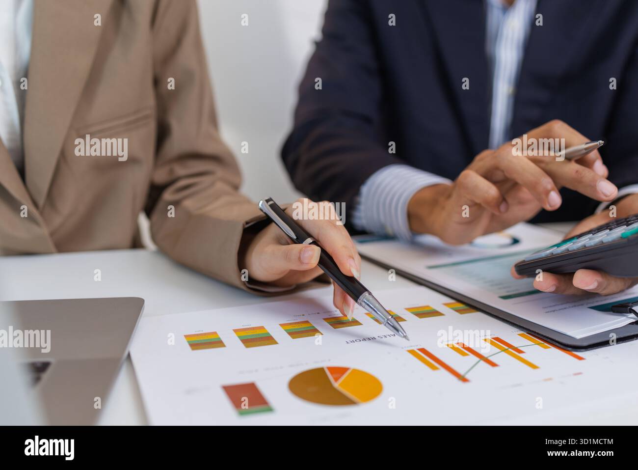 Two business professionals are discussing financial charts and reports ...