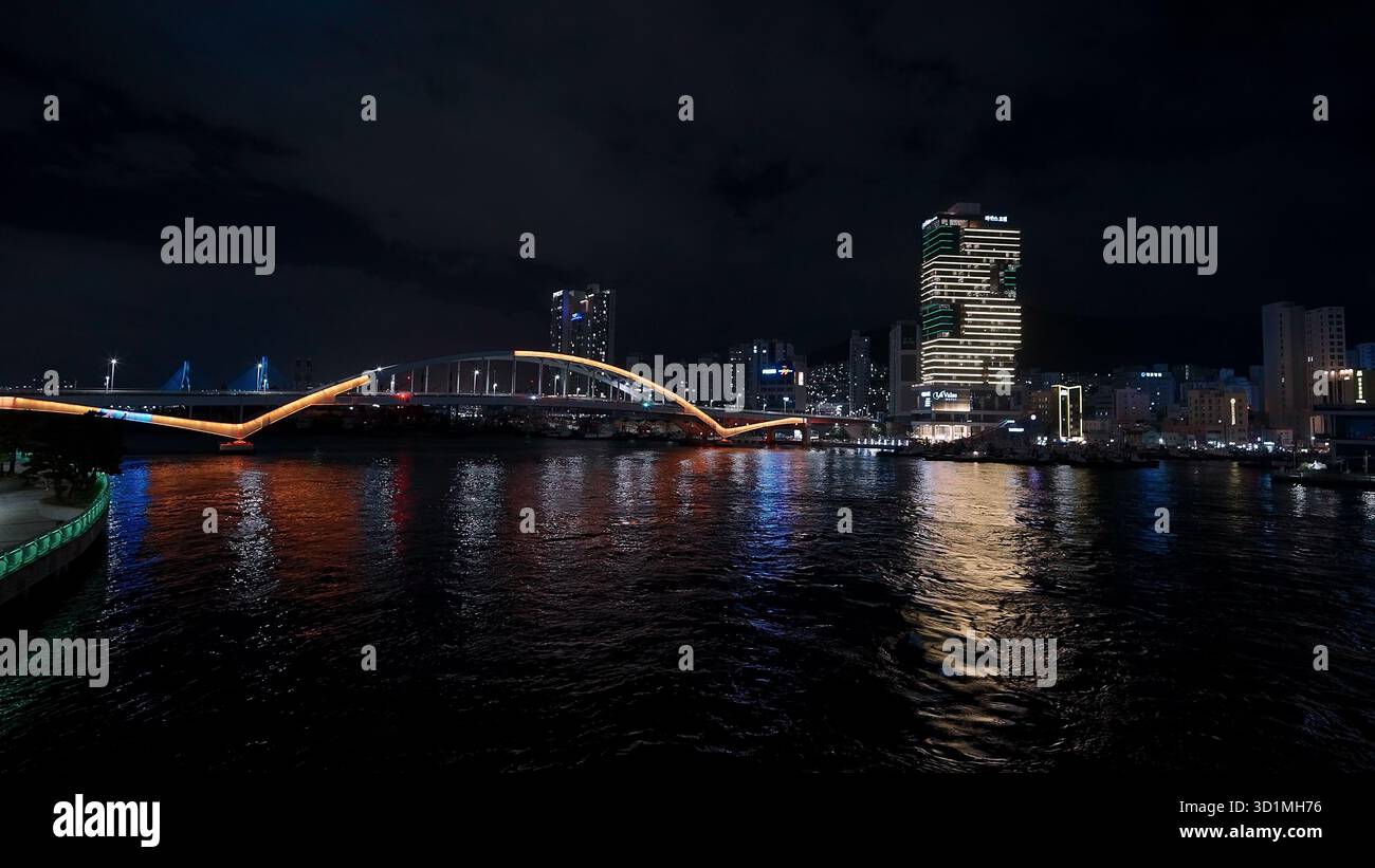 BUSAN, SOUTH KOREA - OCTOBER 10, 2025 - Busan city lights reflecting on the Suyeong river with the APEC Naru Park Bridge Stock Photo