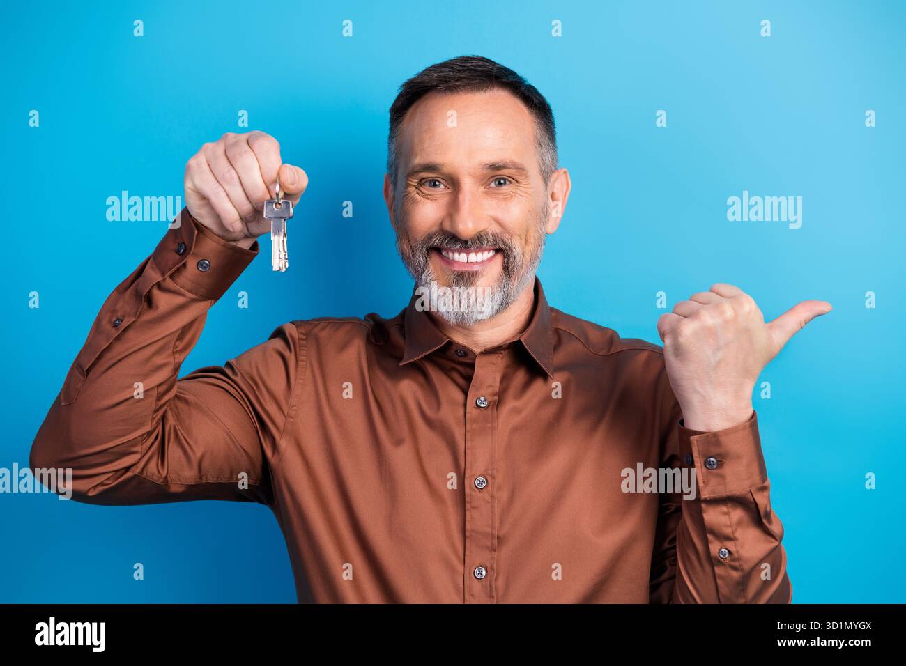 Professional businessman with keys smiles and gives thumbs up against ...