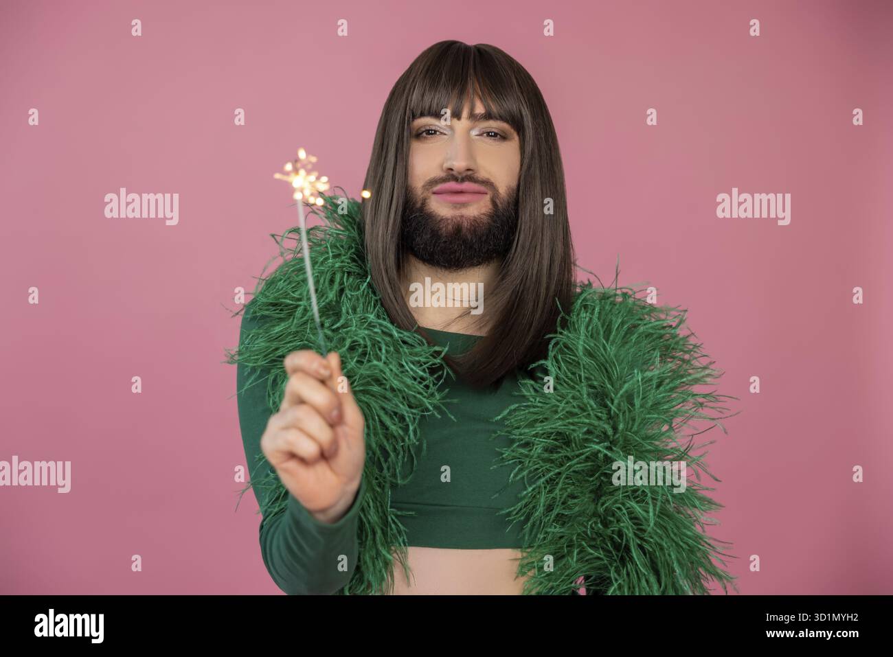 Self confident attractive transgender with makeup and wig wearing green  feather party dress looking at camera with sparkler in hand, posing  isolated o Stock Photo - Alamy