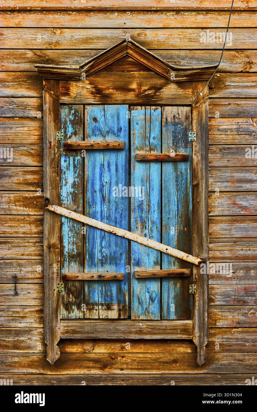 Weathered wooden window in slums painted in peeling blue paint Stock Photo
