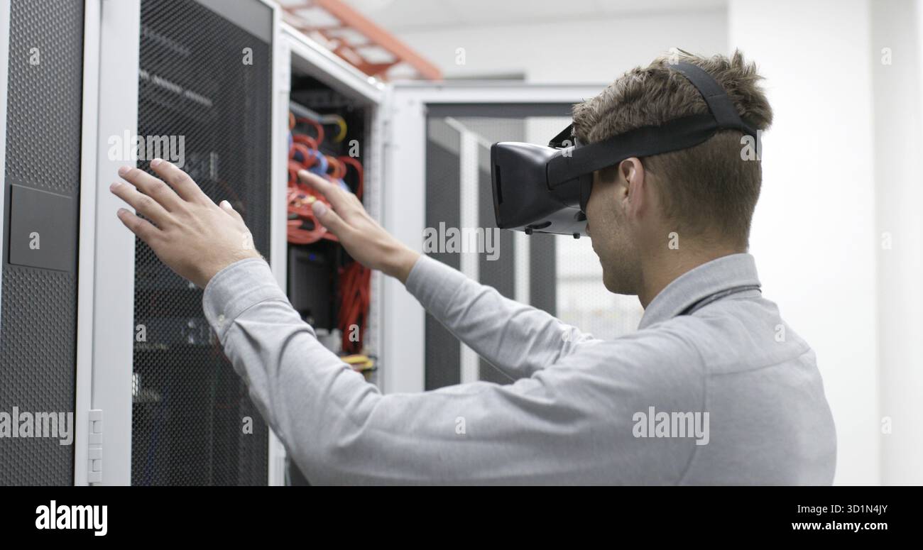Young IT engeneer using virtual reality headset over server room background Stock Photo