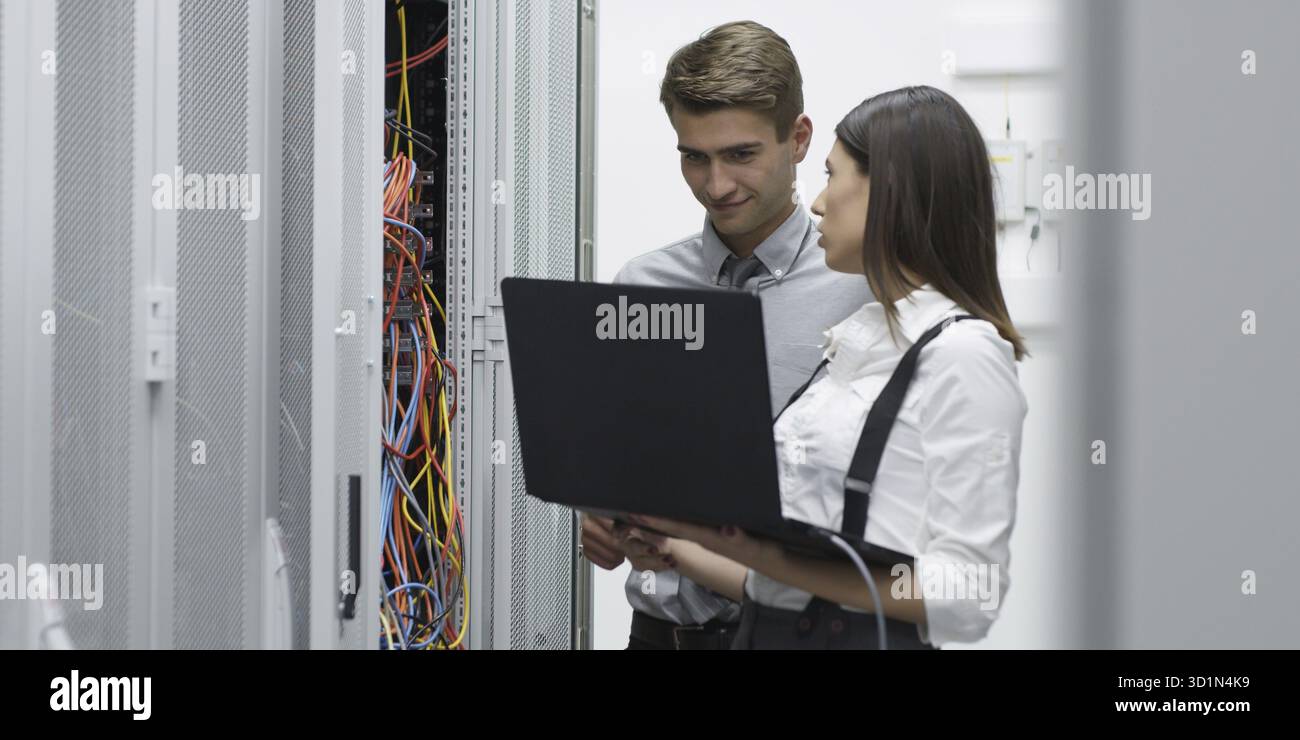Technicians using laptop while analyzing server in server room Stock Photo