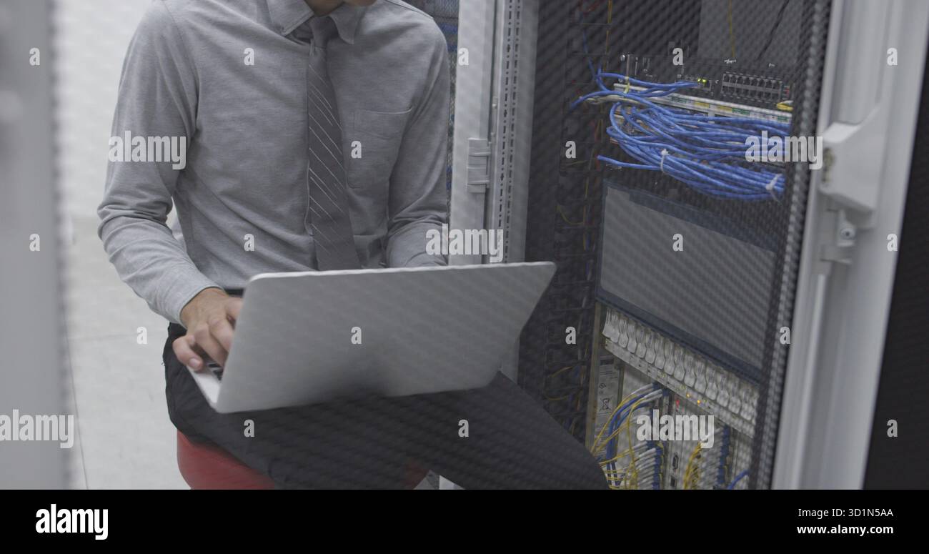 Technician performing maintenance tasks in a server room rack Stock Photo
