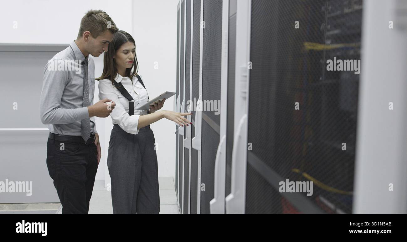 Technicians using laptop while analyzing server in server room Stock Photo