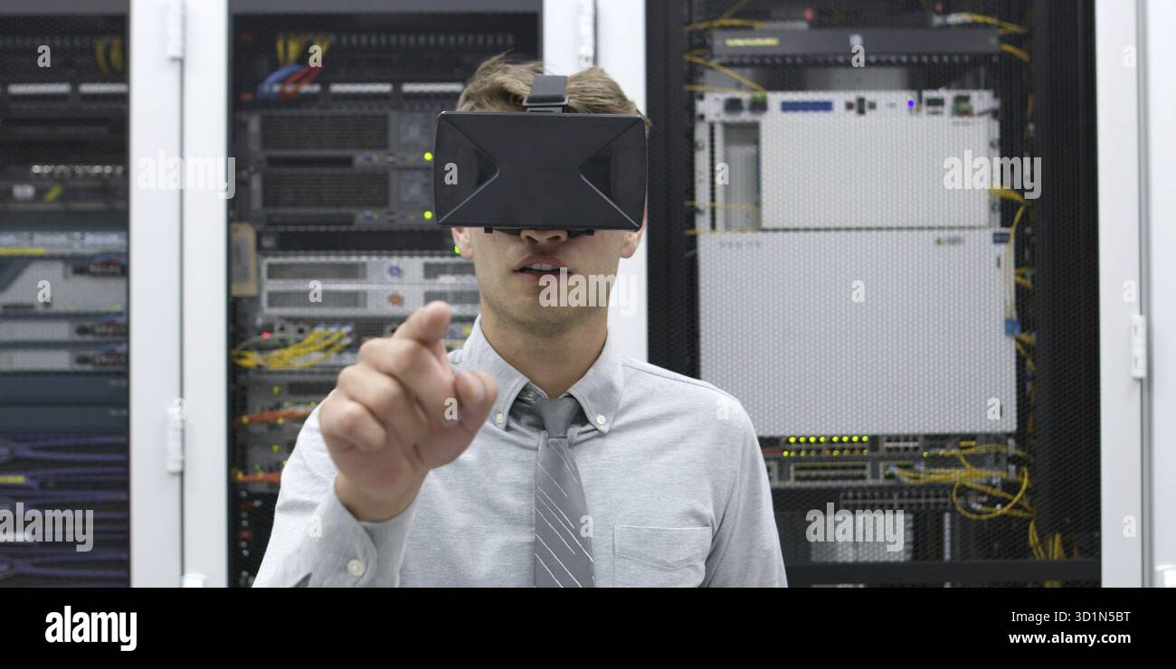 Young IT engeneer using virtual reality headset over server room background Stock Photo