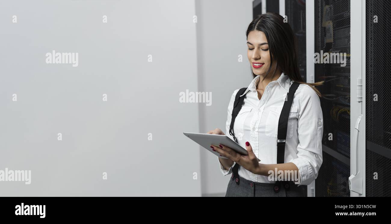 Technician using tablet pc while analysing server in large data center Stock Photo