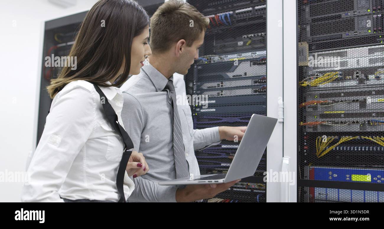 Technicians using laptop while analyzing server in server room Stock Photo