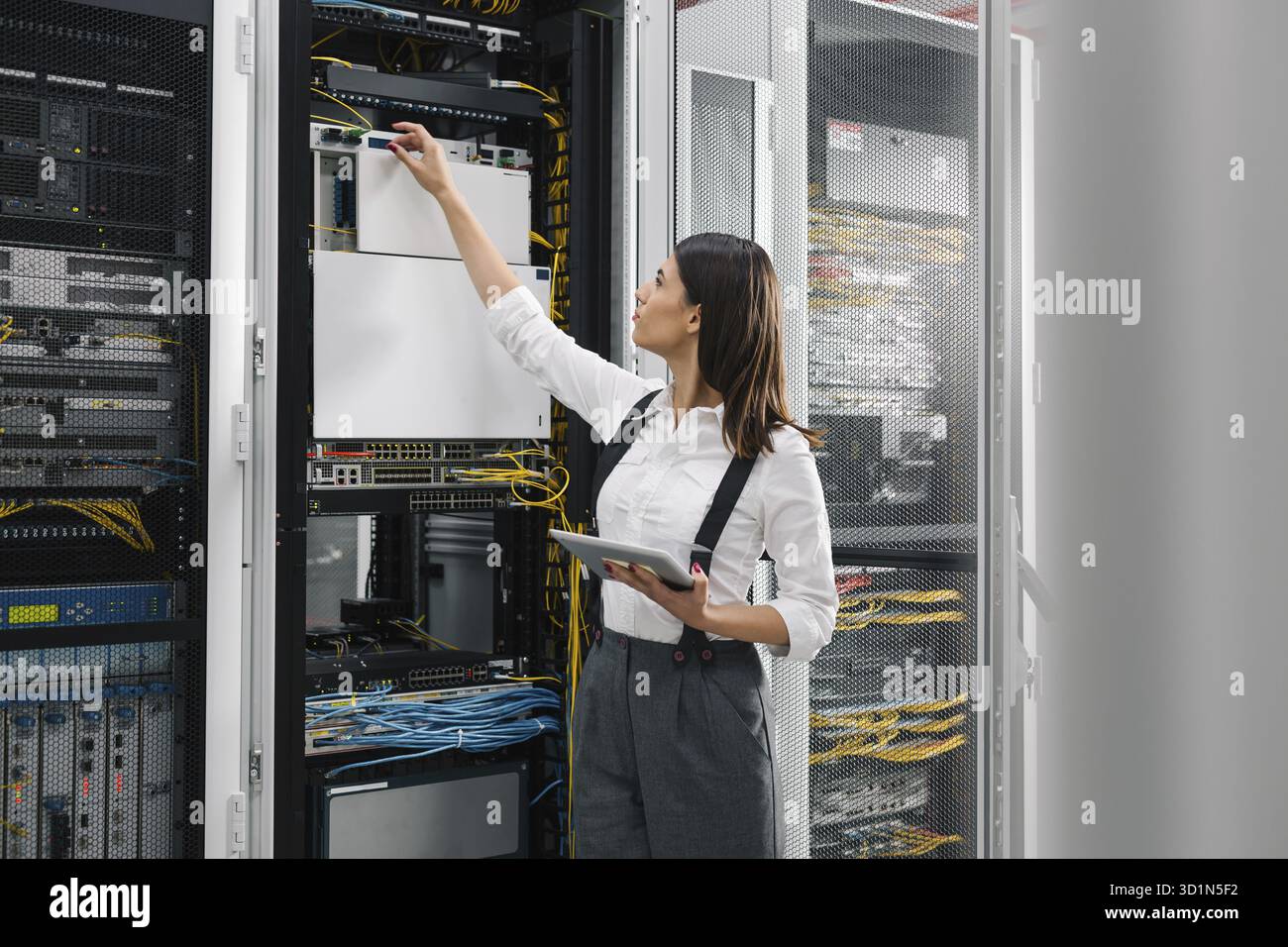 Technician using tablet pc while analysing server in large data center Stock Photo