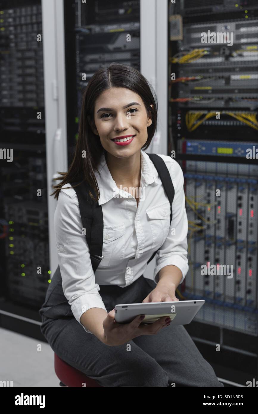 Technician using tablet pc while analysing server in large data center Stock Photo