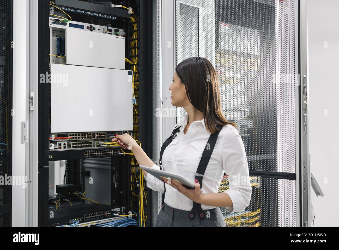Technician using tablet pc while analysing server in large data center Stock Photo